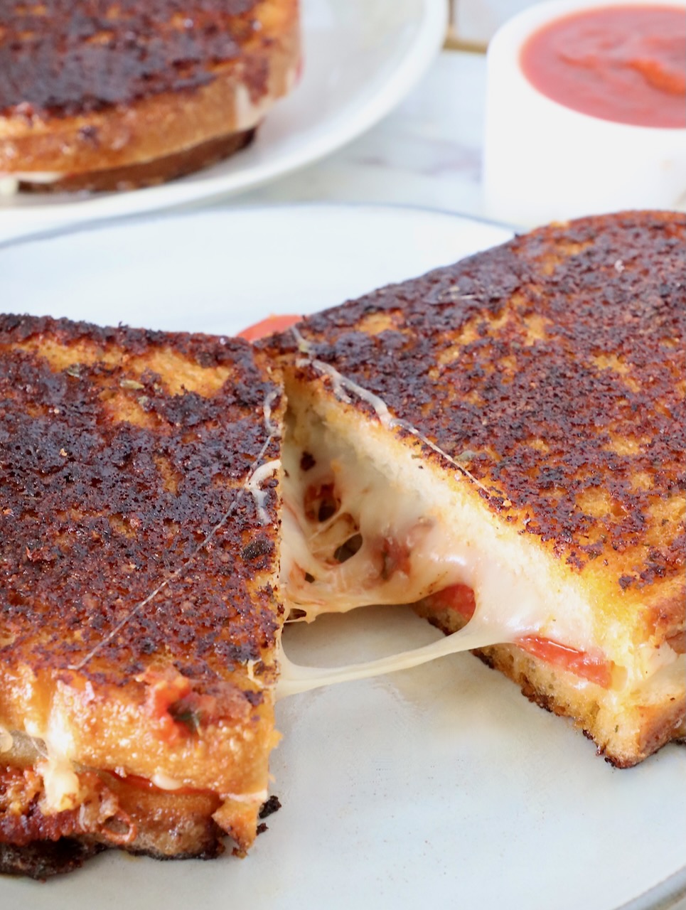 pizza grilled cheese cut in half and pulled apart on a plate