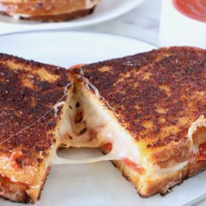 pizza grilled cheese sandwich cut in half and pulled apart on a plate