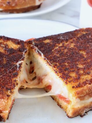 pizza grilled cheese sandwich cut in half and pulled apart on a plate