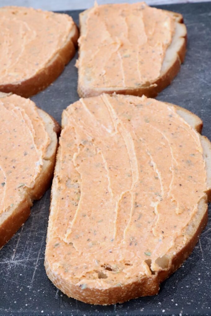 seasoned butter spread on sliced bread on a cutting board