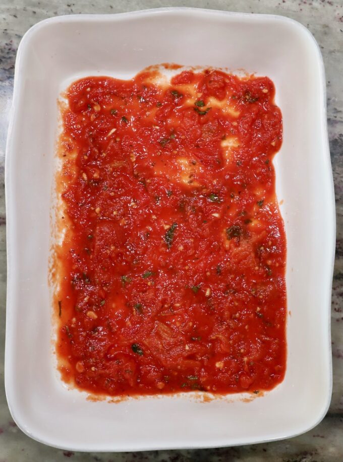 marinara sauce in the bottom of a casserole dish