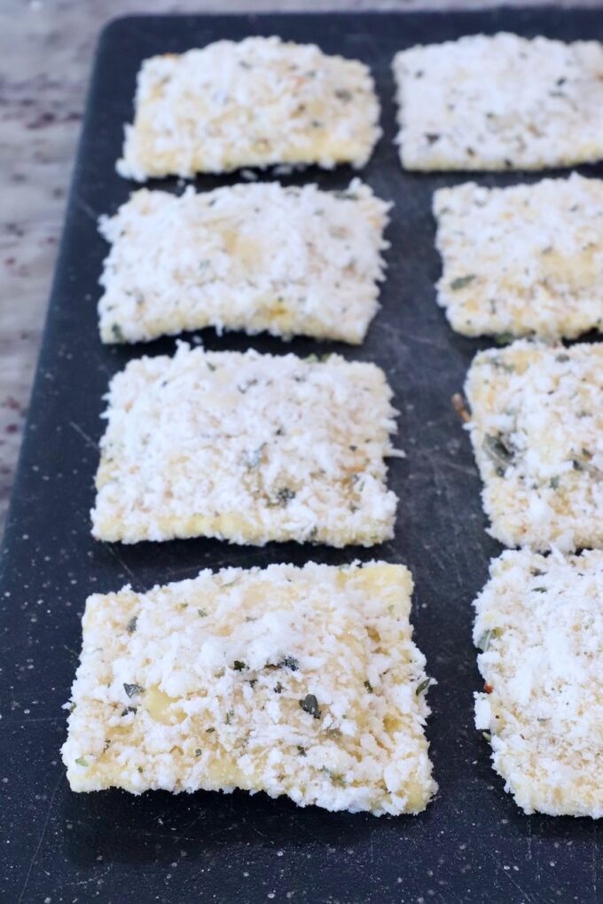 raviolis coated in breadcrumbs on a cutting board