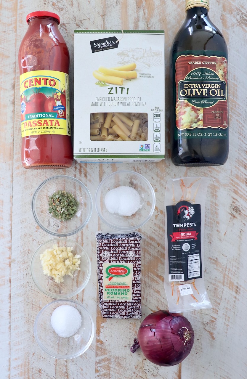 ingredients for nduja tomato sauce on a white wood board