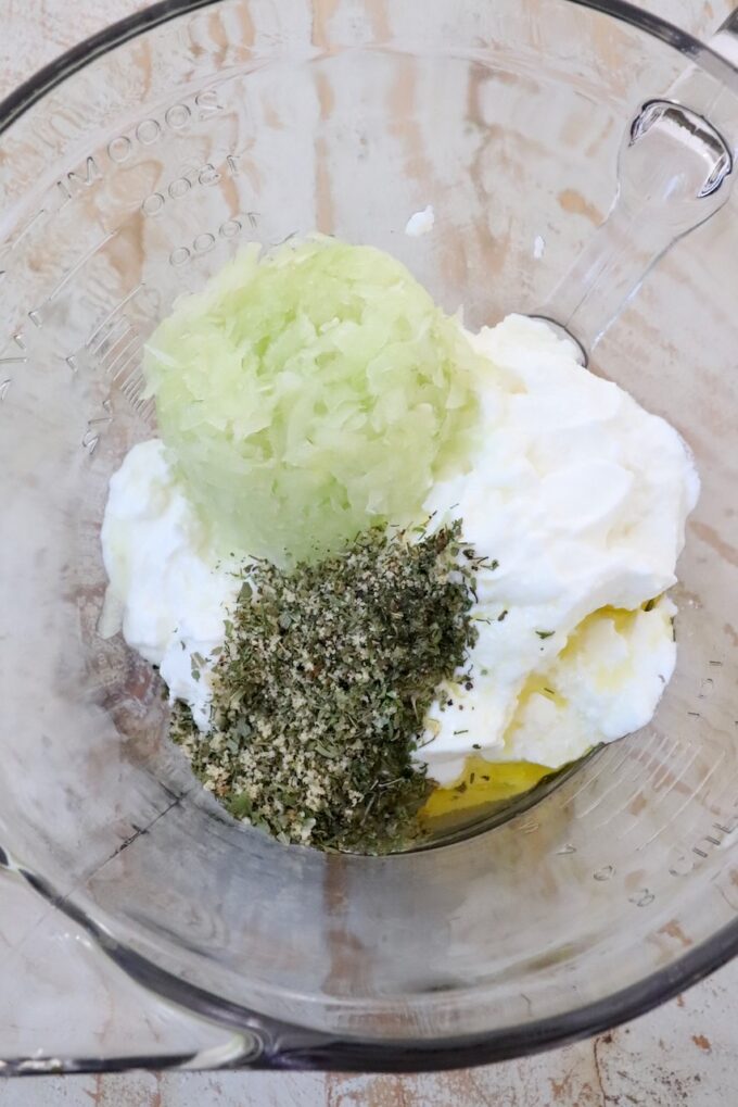 yogurt, grated cucumber, oil and dried herbs and spices in a large glass bowl