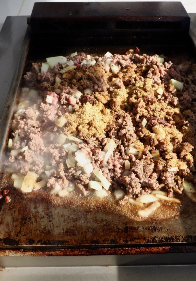 seasoned ground beef on a flat top griddle