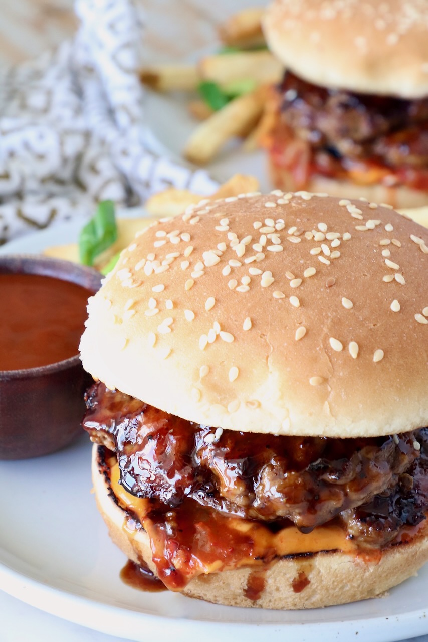 prepared burger on a plate with korean bbq sauce and french fries