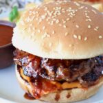 burger covered in bbq sauce on a plate