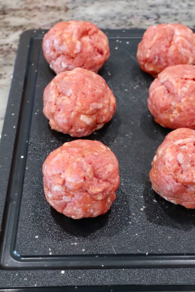 balls of seasoned ground beef and pork on a cutting board