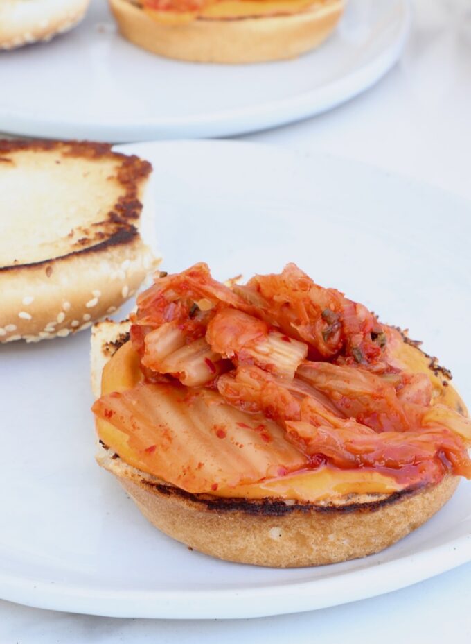 hamburger bun on a plate topped with gochujang mayo and kimchi