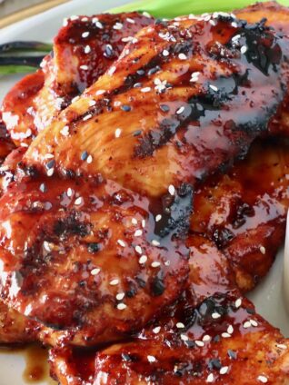 bbq glazed grilled chicken stacked up on a plate