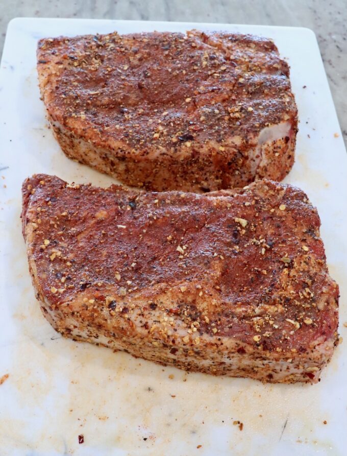 seasoned ribeye steaks on a cutting board