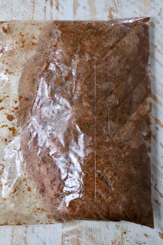 skirt steak marinating in shawarma seasoning in a large plastic zipper bag