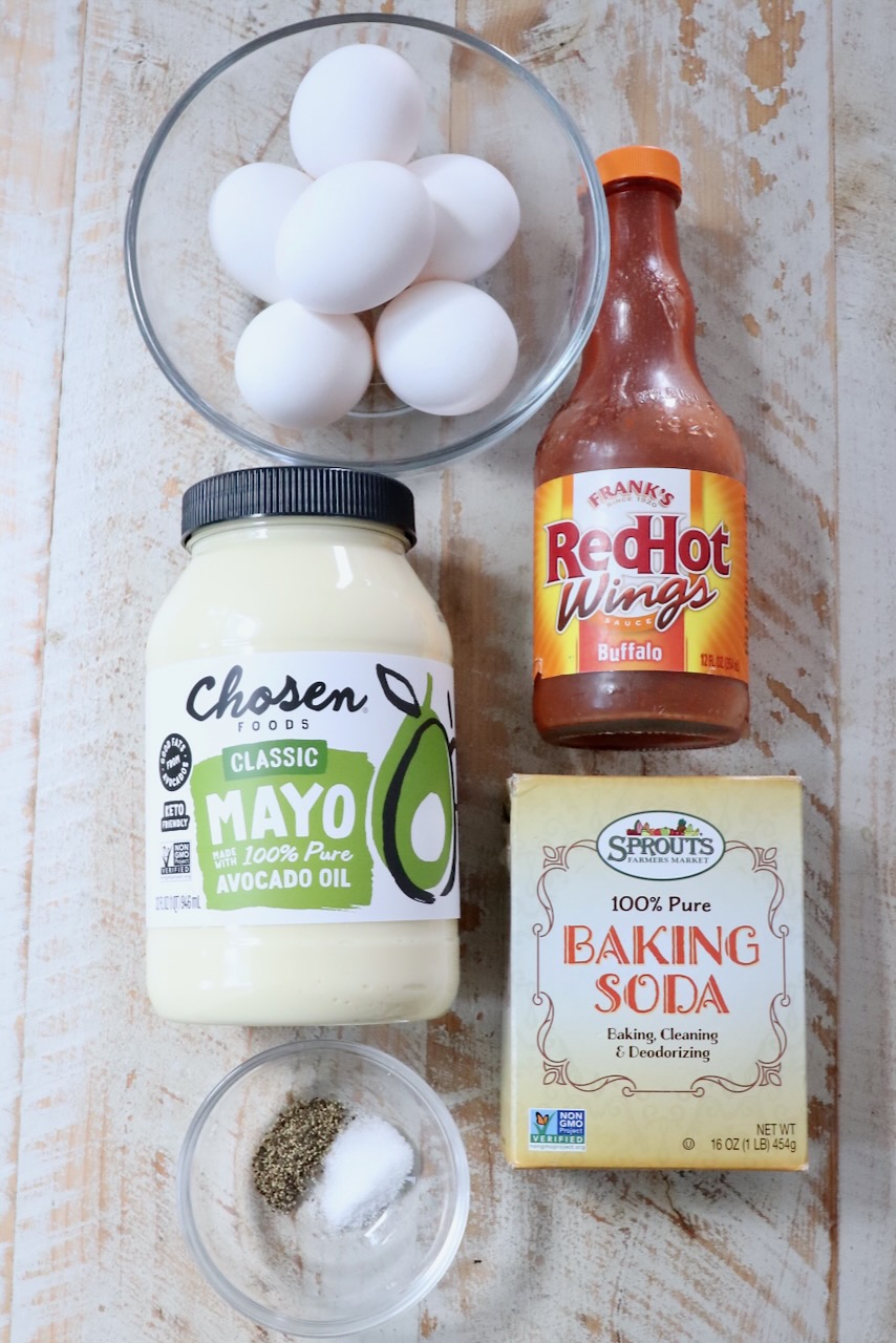 ingredients for buffalo deviled eggs on a white wood board
