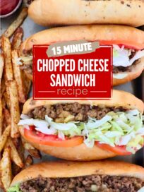 four chopped cheese sandwiches with sliced tomatoes and shredded lettuce inside the sandwiches, lined up on a baking sheet with seasoned, cooked french fries on the side