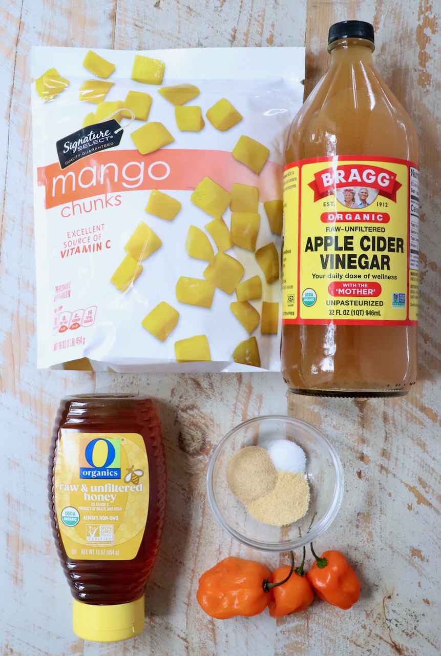 ingredients for mango habanero sauce on a white wood board