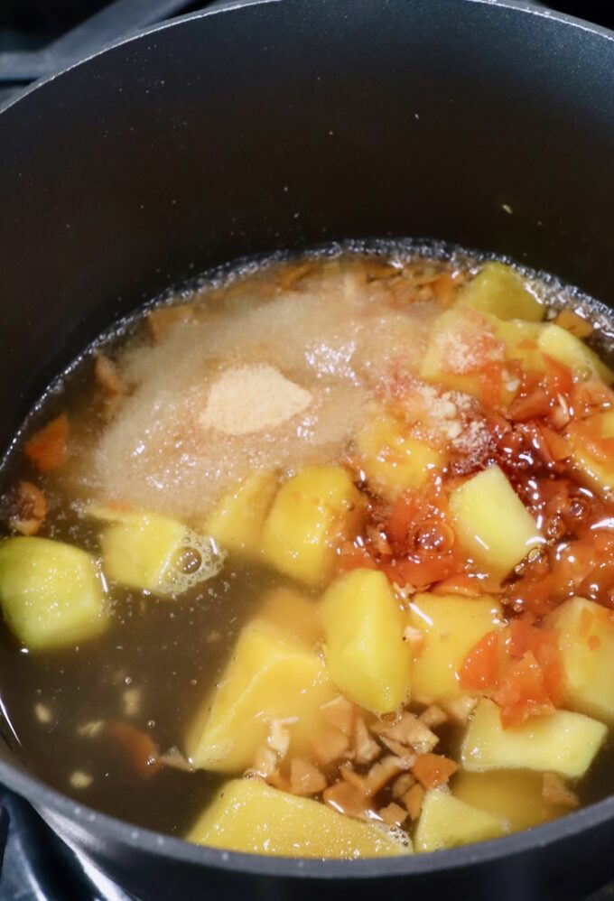 chunks of mango in a sauce pan with honey, vinegar, garlic powder and minced habanero peppers