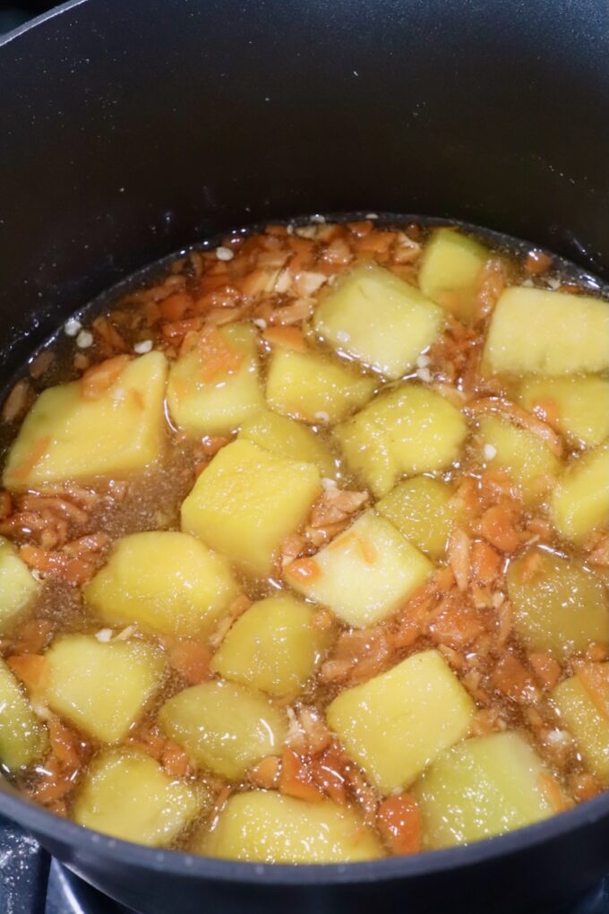 chunks of mango in a sauce pan with honey, vinegar and minced habanero peppers