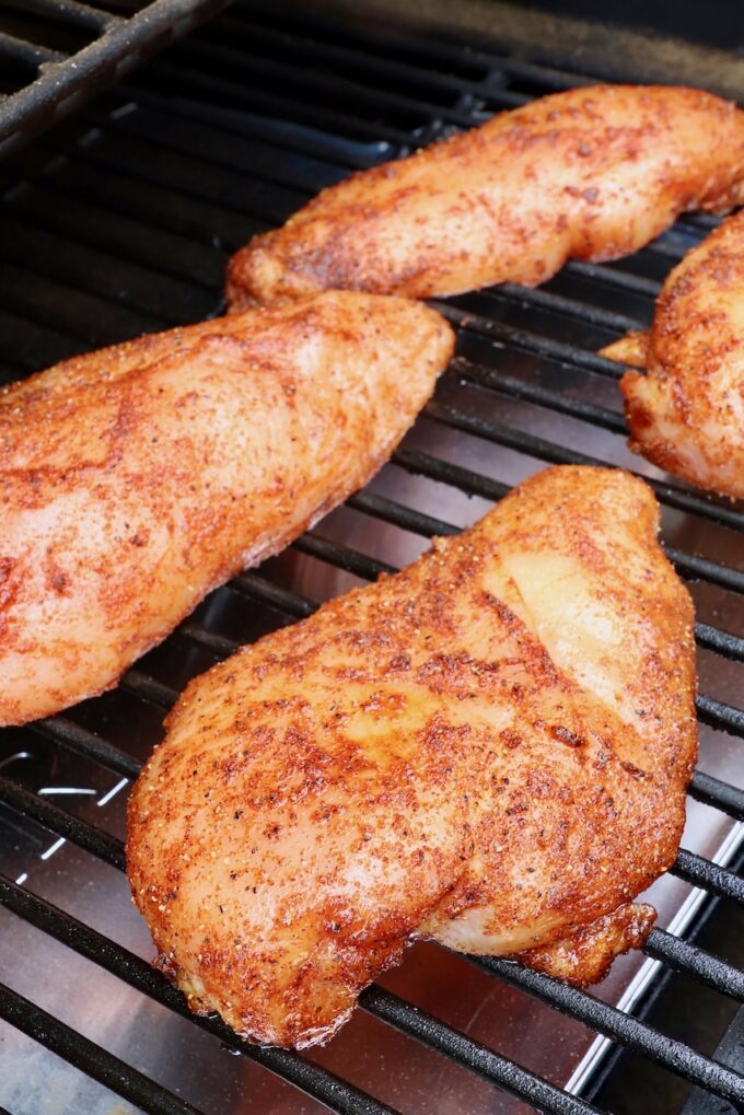 seasoned chicken breasts on a smoker