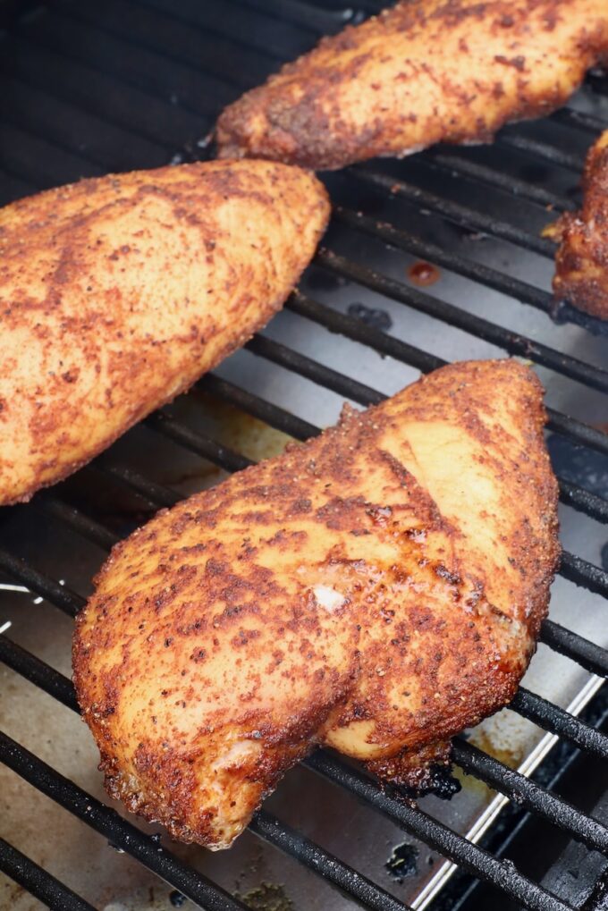 cooked seasoned chicken breasts on a smoker