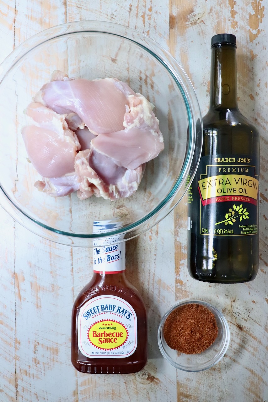 ingredients for smoked chicken thighs on a white wood board