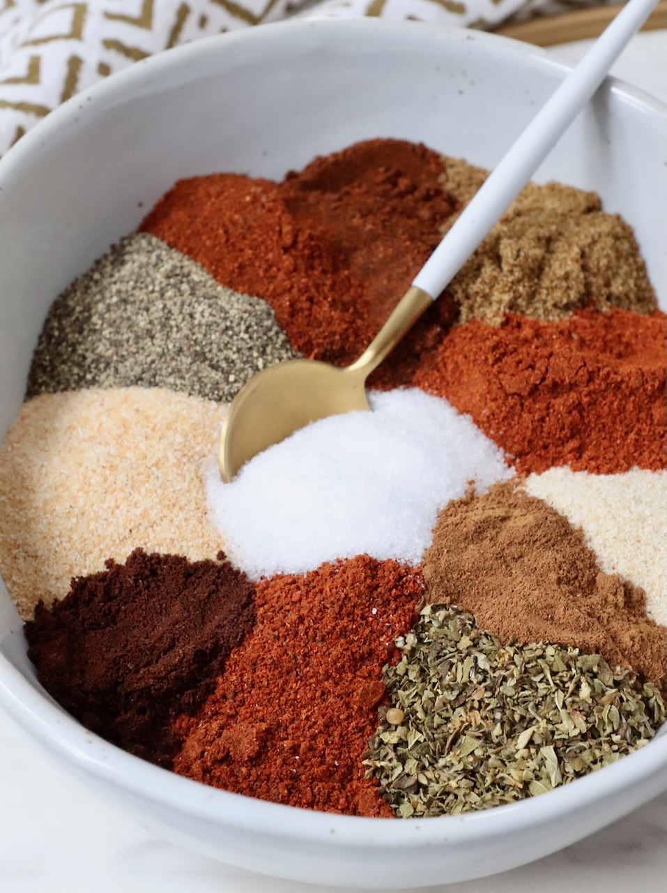 dried herbs and spices separated in a bowl with a spoon