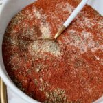 dried herbs and spices mixed together in a bowl with a spoon