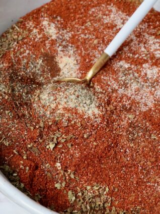 dried herbs and spices mixed together in a bowl with a spoon