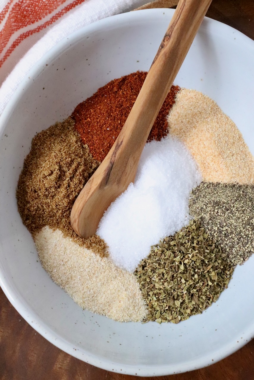 dried herbs and spices separated in a bowl with a wooden spoon