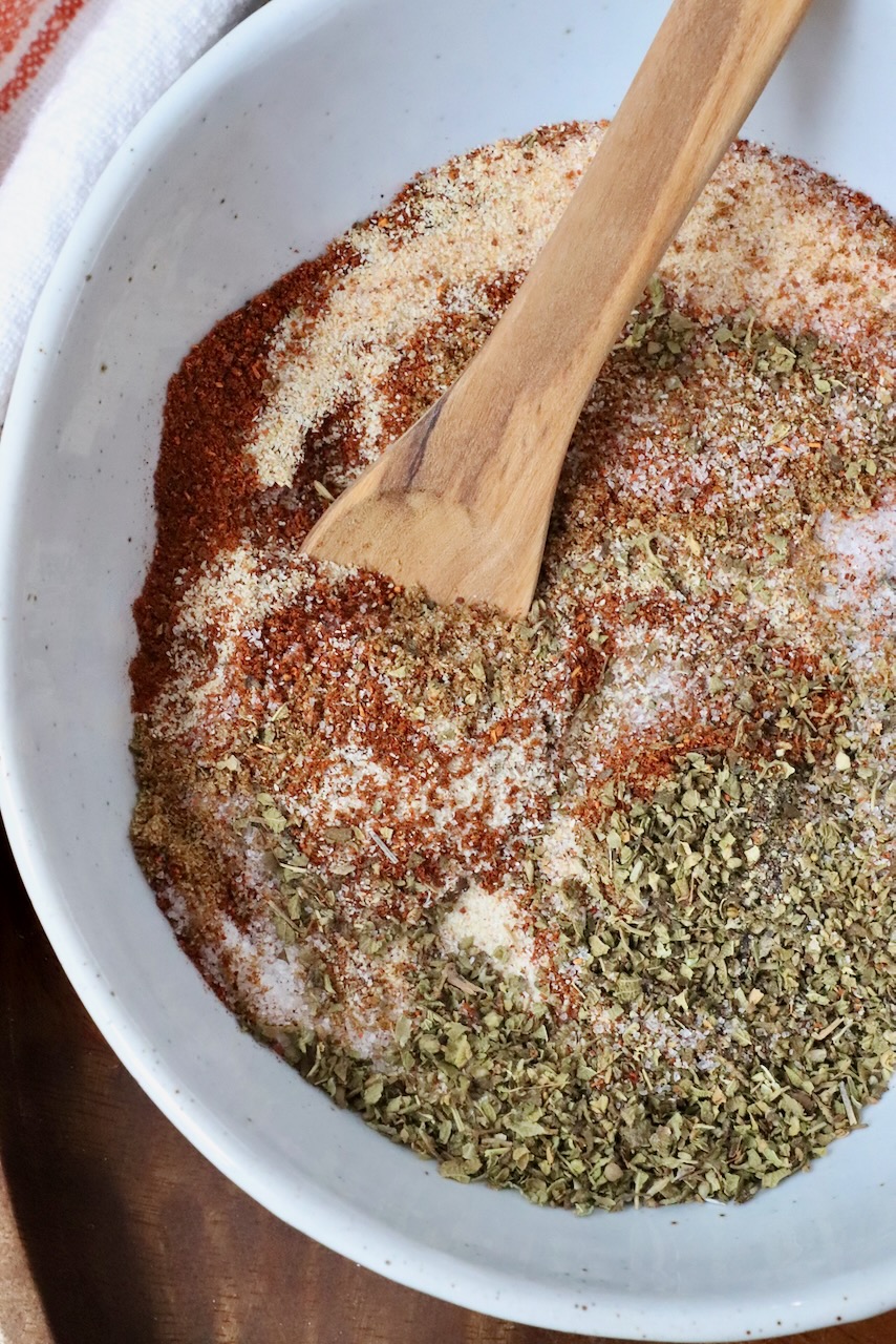carnitas seasoning mixed together in a bowl with a wooden spoon