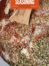 dried herbs and spices combined in a bowl with a wooden spoon