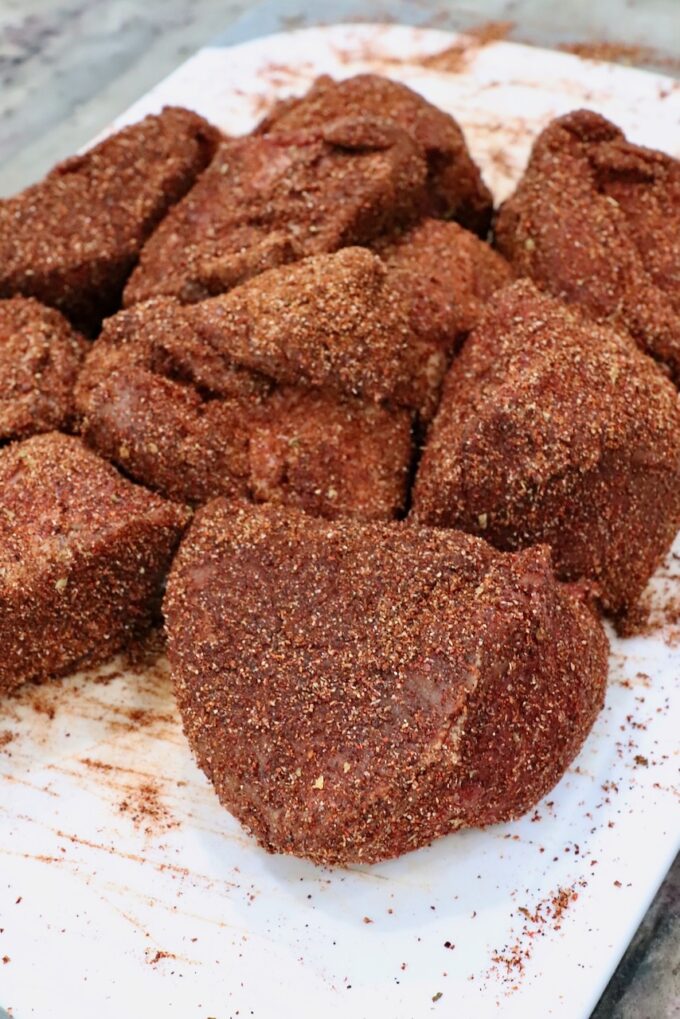 seasoned chunks of beef on a white cutting board