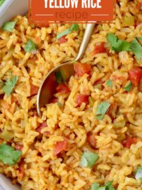 yellow rice in a bowl with a spoon topped with fresh cilantro leaves