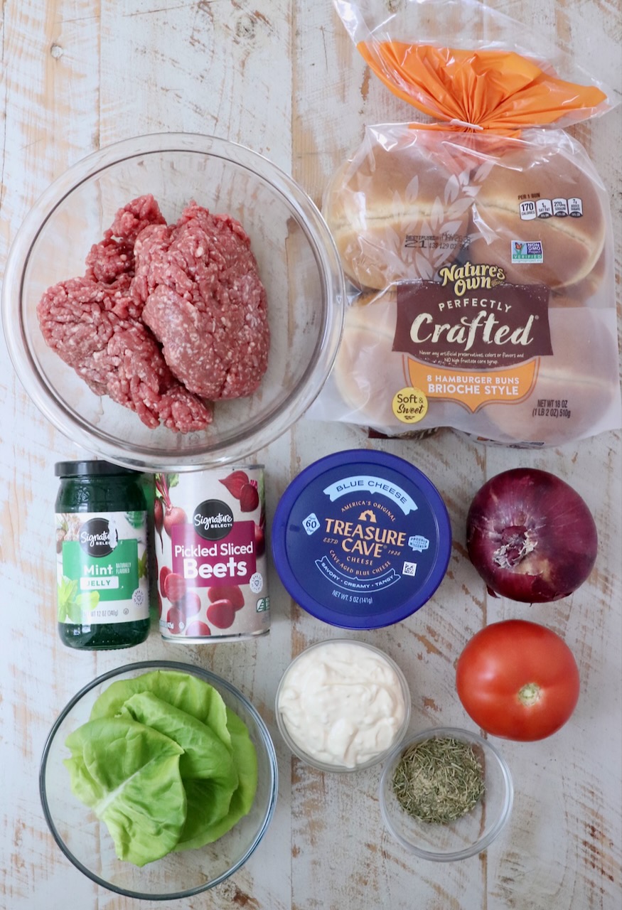 ingredients for lamb burger on a white wood board