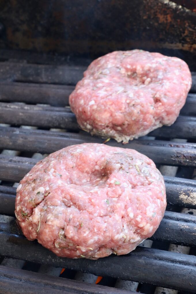 raw lamb burger patties on a grill