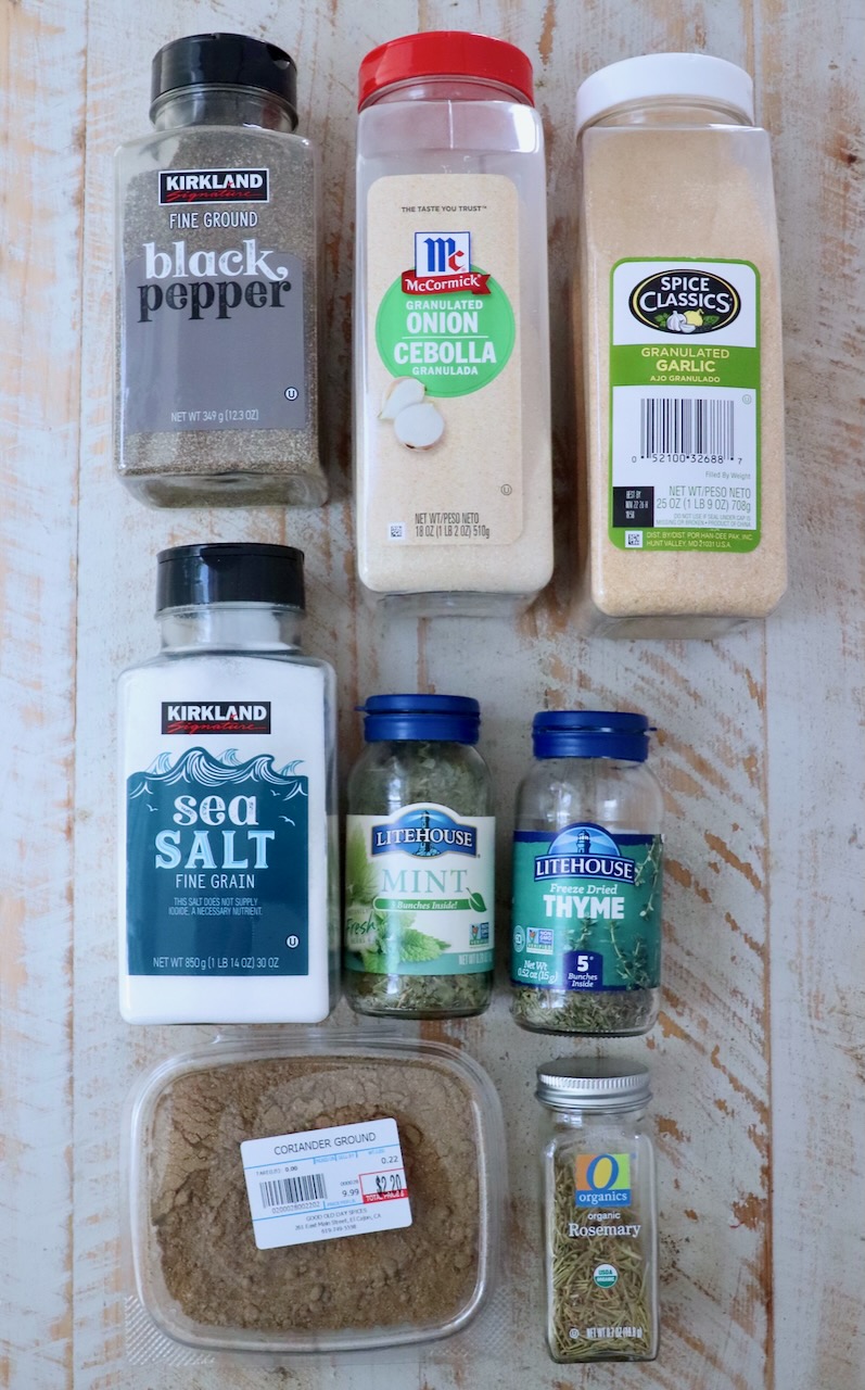 dried herbs and spices in plastic containers on a white wood board