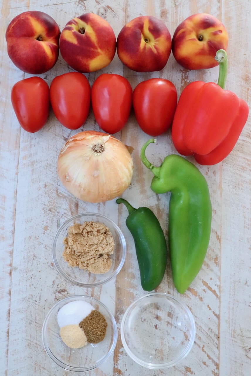 ingredients for peach salsa on a white wood board