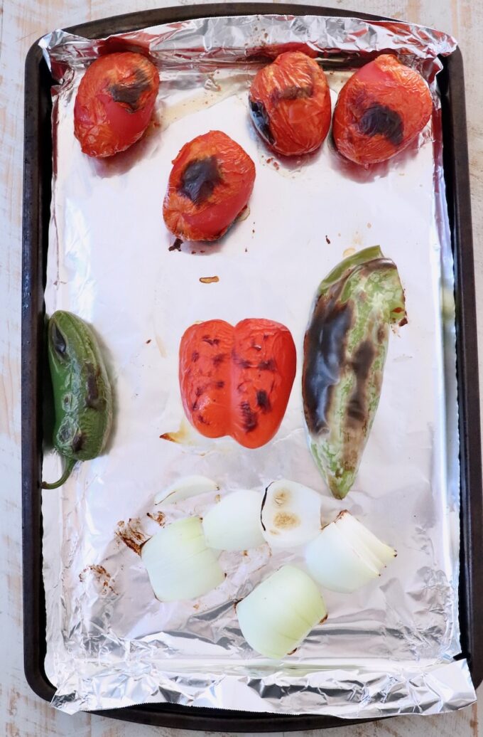 roasted roma tomatoes, peppers and onions on a foil lined baking sheet