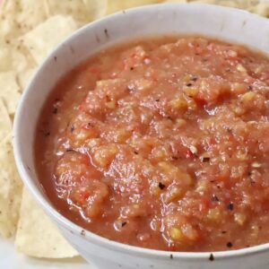 peach salsa in a bowl surrounded by tortilla chips