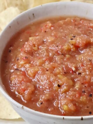 peach salsa in a bowl surrounded by tortilla chips
