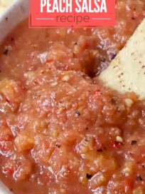 tortilla chip dipped into a bowl of peach salsa