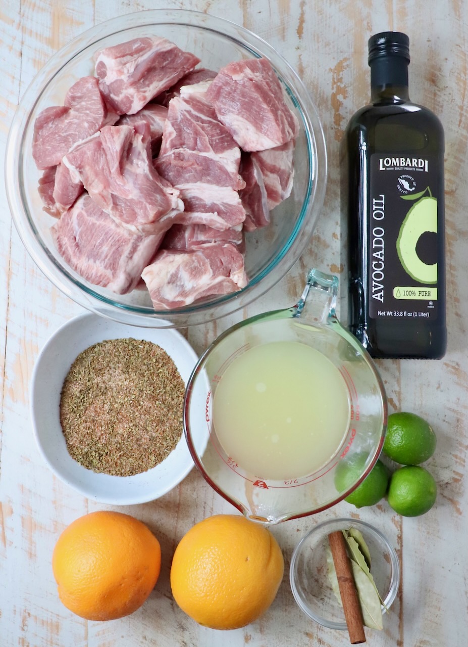 ingredients for carnitas on a white wood board