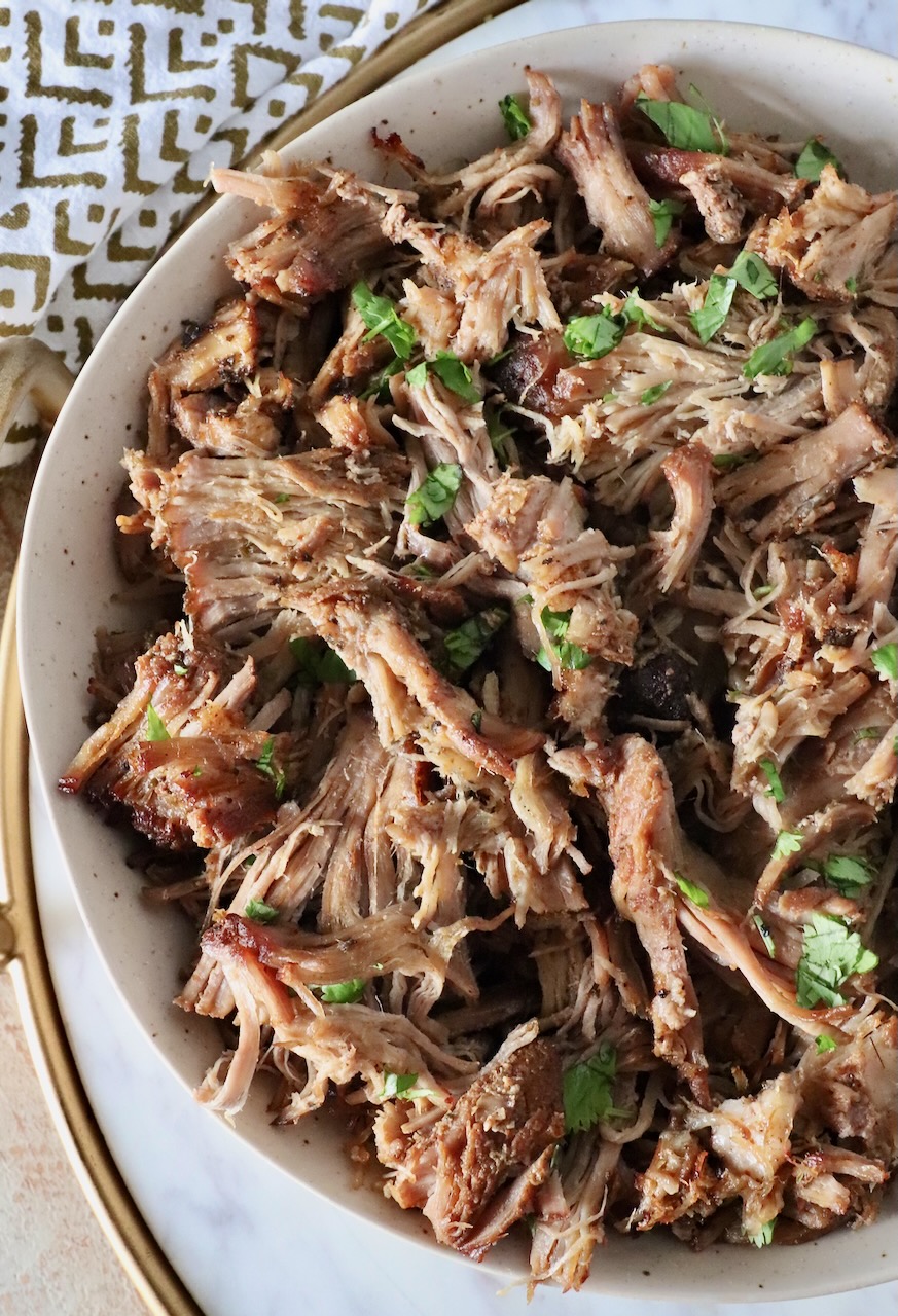shredded pork carnitas in a bowl with fresh cilantro sprinkled on top