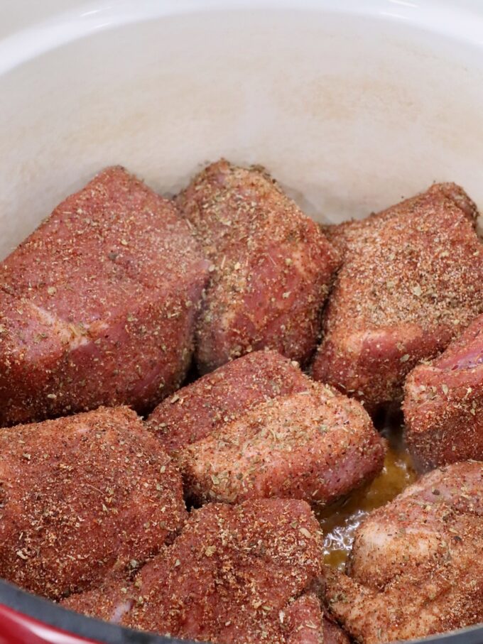 seasoned pieces of pork in a large cast iron dutch oven