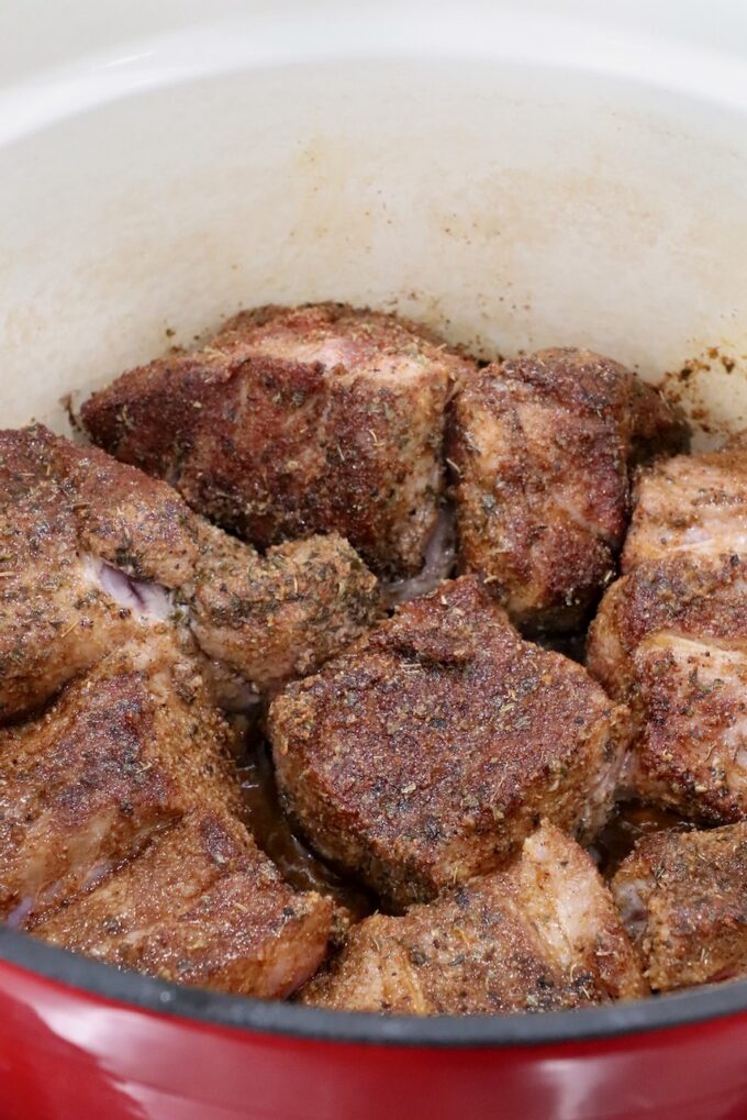 seared, seasoned pieces of pork in a large cast iron dutch oven