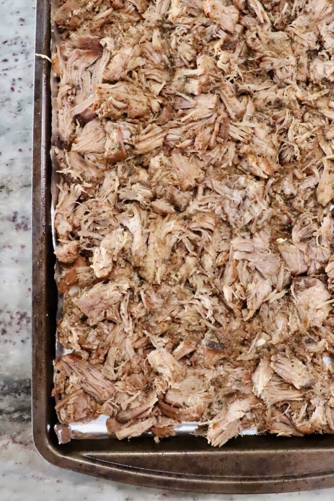 shredded pork spread out on a baking sheet
