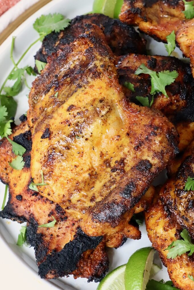grilled chicken thighs stacked up on a plate
