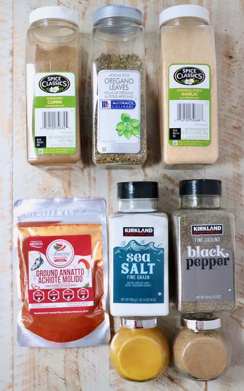 ingredients for sazon seasoning in containers on a white wood board