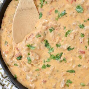 smoked queso dip in a skillet with a wooden spoon