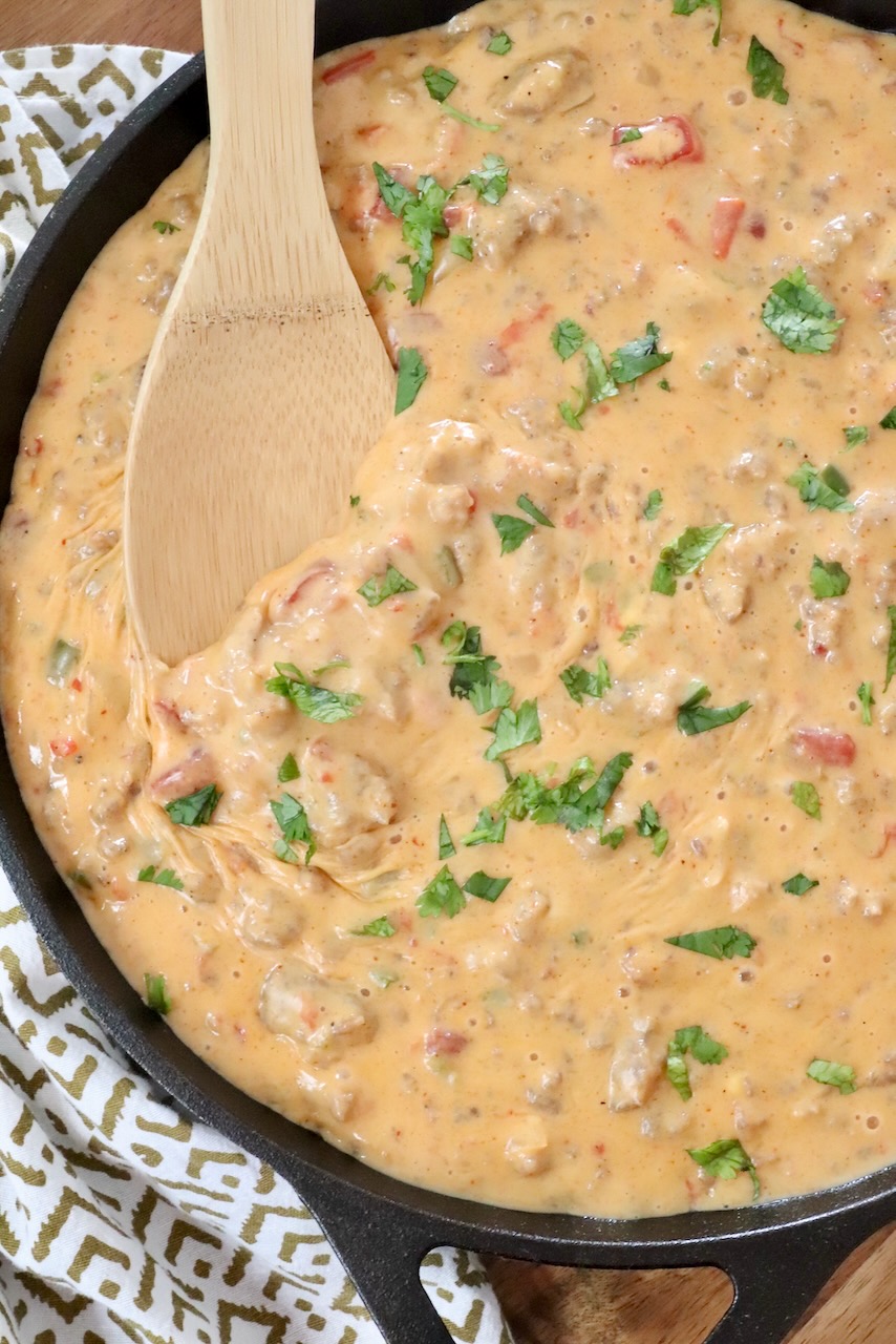 smoked queso dip in a skillet with a wooden spoon