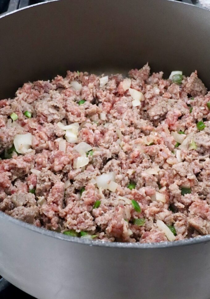 cooked sausage in a large pot with diced onions and jalapenos